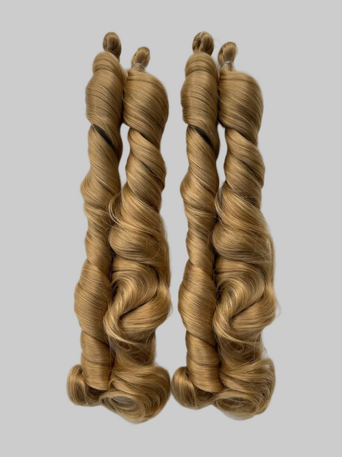 Two braided blonde hair extensions on a white marble surface